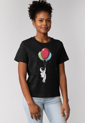 Schwarzes Baumwoll-T-Shirt mit einem Astronauten-Graphic, der drei bunte Ballons vor einem sternenübersäten Hintergrund hält. Kurze Ärmel und klassischer Schnitt.