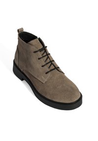 Wildleder-Stiefeletten in gedecktem Taupe mit runder Zehenpartie, Schnürverschluss, dünner schwarzer Gummisohle und kontrastierenden Nähdetails.