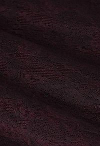 Tissu en dentelle bordeaux présentant des motifs complexes avec une surface texturée, affichant une chute douce et une broderie détaillée.