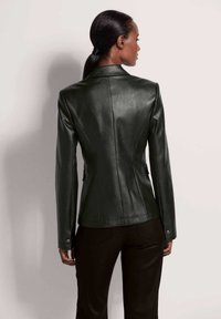 Groene leren blazer met een getailleerde pasvorm, puntige kraag, verticale naden en knoopmanchetten, die een stijlvolle en gladde textuur laat zien.