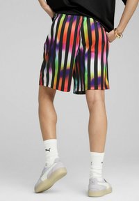 Multifarvede stribede shorts med sorte detaljer, fremstillet af et let og glat materiale samt en elastisk talje.