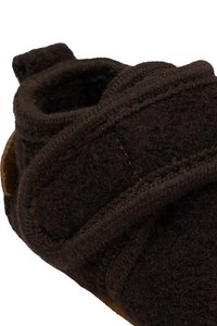 Tumepruun villaste sussid pehme tekstuuriga; omavad ümarat kuju, Velcro kinnitamist ja kontrastset beeži nahksippet.