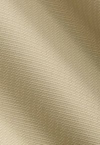 Gestructureerde beige stof met een gewoven patroon, die een subtiele glans en een zachte, tastbare oppervlakte vertoont. Ideaal voor stoffering of gordijnen.