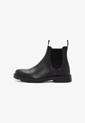 Bottines Chelsea en cuir noir avec des panneaux élastiques sur les côtés, des languettes de tirage et une semelle robuste. Texture lisse avec un design élégant et moderne.