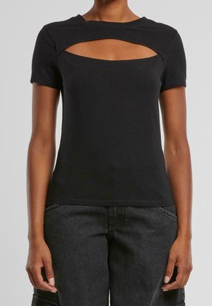 Kobieta nosząca dopasowany czarny krótki top z poziomym wycięciem na klatce piersiowej oraz ciemnoszare spodnie z wysokim stanem.