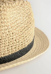 Geweven strohoed in natuurlijk beige met een zwarte gevlochten band. Ronde kroon en brede rand, met een gestructureerde afwerking.