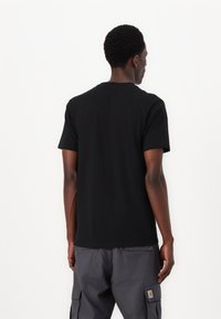 Zwarte katoenen T-shirt met een klassieke ronde hals, korte mouwen en een relaxte pasvorm, weergegeven vanuit de achterkant op een witte achtergrond.