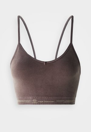 Brown ribbed seamless sports bra with thin straps and "Yoga Searcher" branding on the elastic band at the bottom.