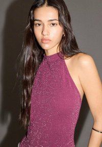 Top s halterom v hlbokej burgundskej farbe, vyrobený z textúrovanej látky s lesklým povrchom a trblietkami, ktorý odhaľuje plecia a kľúčnu kost.