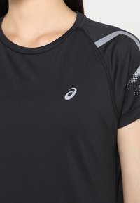 Schwarzes sportliches T-Shirt aus glattem Stoff, mit rundem Ausschnitt, kurzen Ärmeln und einem silbernen Logo auf der Vorderseite sowie Schulterakzenten.