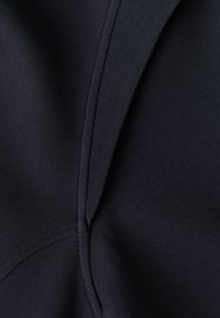 Acercamiento de una tela oscura con textura suave, con costuras y detalles de costura visibles, que muestra una paleta de colores en tonos negros.