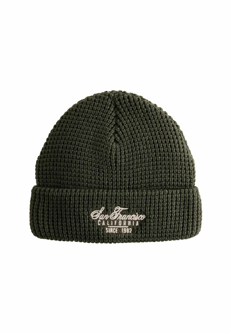 Bonnet en tricot vert avec une texture côtelée, présentant un revers tourné et un texte brodé indiquant "San Francisco Californie Depuis 1982."