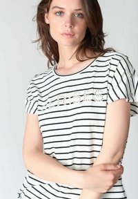 Camiseta de rayas blancas y negras con cuello redondo, mangas cortas con detalles de botones y un texto de cuentas en el frente.