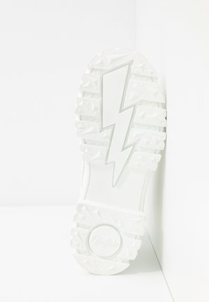 Biała podeszwa trampka o teksturowanej powierzchni, z motywem błyskawicy i okrągłym logo "Buffalo". Wzory bieżnika zapewniają przyczepność.