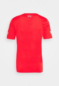 Camiseta roja de manga corta hecha de tela suave, con un cuello redondo y un logo en la parte superior de la espalda y en la manga izquierda.