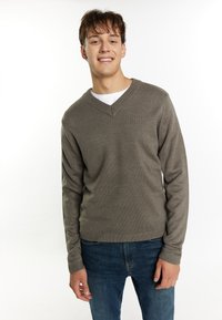 Maglione grigio a maglia con scollatura a V e polsini a coste, abbinato a jeans in denim blu. Il tessuto ha una consistenza liscia e una vestibilità comoda.