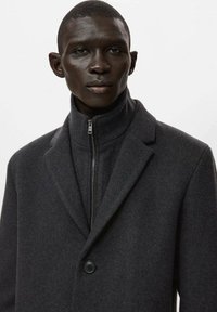 Abrigo de lana gris oscuro con cuello alto, cremallera frontal y cierre de un solo botón. Textura suave con diseño entallado.