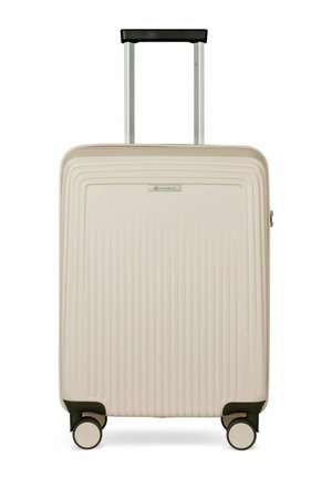 Valise rigide beige avec des rainures verticales, quatre roues et une poignée noire rétractable déployée.