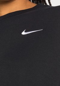 Black cotton sweatshirt with ribbed crew neckline, featuring a white Nike logo on the chest. Soft texture and casual fit.