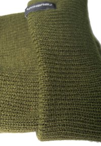 Green knitted fabric with a textured pattern, featuring a visible black label. The material appears soft and flexible.