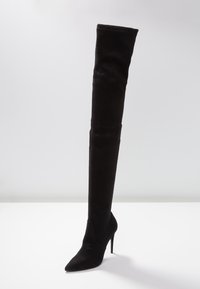 Stivale nero sopra il ginocchio in suede, con punta a forma di freccia e alto tacco a stiletto. Il design è elegante con accenti minimi.