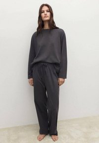 Sada loungewear v tmavě šedé bavlně obsahující top s dlouhým rukávem a kalhoty na šňůrku s volným střihem a jemnou texturou.