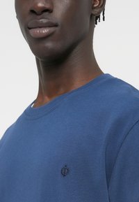 Μπλε βαμβακερό φούτερ με στρογγυλή λαιμόκοψη και μικρό, σκούρο κεντημένο λογότυπο στο αριστερό στήθος. Ομαλή υφή και casual εφαρμογή.