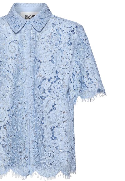 Lyseblå kortærmet blondebluse med blomsterprint, bølgede kanter og en klassisk krave.