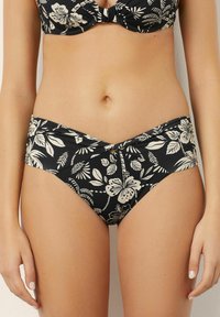 Pantaloni de baie negri cu un model floral alb, av�ând un design răsucit în față și detalii plisate pe laterale.