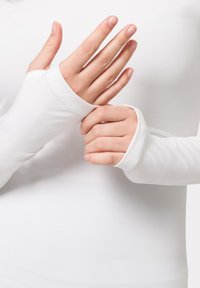 Biała bluzka z długim rękawem i dopasowanymi mankietami. Wykonana z gładkiego, elastycznego materiału. Ręce widoczne, pokazujące bezpalczastą konstrukcję i miękką teksturę.