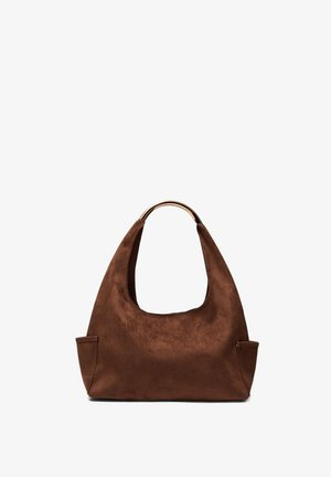 Sac à main en daim marron avec une poignée incurvée en métal doré et deux petites poches latérales, présenté sur un fond blanc.