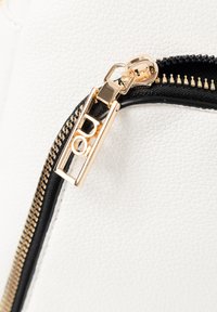 Borsa in pelle bianca testurizzata con cerniera nera e dettagli in oro. Il tirazip presenta un design rettangolare con logo in rilievo.