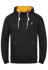 Zwarte hoodie met een gele binnenkant, witte koorden en goudkleurige accenten. Voorzien van een voorzak en elastische manchetten.