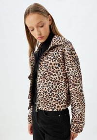 Beige und brauner, taillierter Leopardmuster-Jacke mit Reißverschluss, zwei Taschen und gerafften Bündchen. Strukturierter, leichter Stoff.