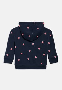 Nīkotras zilas krāsas kapucveida sporta krekls ar izkliedētām rozā sirsniņu raksta, garām piedurknēm un ribveida aprocēm, attēlots no aizmugures.