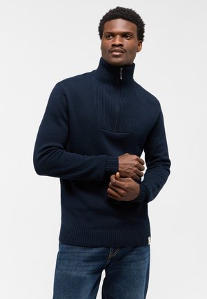 Suéter de punto azul marino con cuello alto y media cremallera. Presenta una textura acanalada en el cuello y los puños. Tejido de mezcla de algodón, ajuste casual.