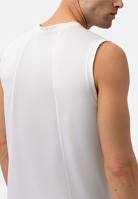 Weißes ärmelloses Sportshirt aus strukturiertem Stoff, mit einem runden Ausschnitt und nahtlosem Rückendesign, das die Schultern betont.