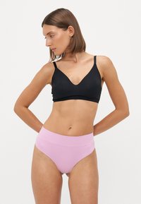 Black v-neck bra with thin straps paired with high-waisted light pink underwear. Both garments feature a smooth, stretchy fabric.