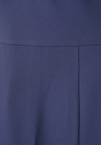 Tissu bleu marine avec une couture horizontale et un détail de pli vertical créant des plis structurés.