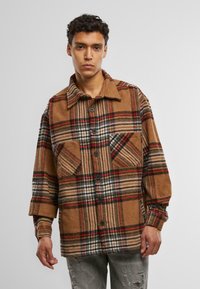 Bruine en zwarte geruite shirtjas van een wolmix, met twee voorzakken, knoopsluiting en een omklapbare kraag. Gestructureerd ontwerp.