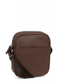 Borsa a tracolla in pelle marrone con una texture liscia, forma quadrata, chiusura con zip superiore e tracolla in tessuto regolabile. Dettaglio della tasca frontale visibile.