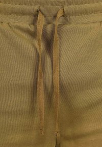 Pantaloni della tuta verde oliva con coulisse realizzati in un tessuto testurizzato, caratterizzati da un motivo a spina di pesce sulle stringhe e una finitura morbida.