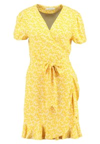 Robe portefeuille jaune à manches courtes, avec des motifs floraux blancs, un décolleté en V, une taille à nouer et un ourlet évasé. Tissu doux et léger.