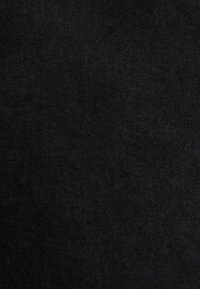Tejido de mezclilla negra con una textura suave y un sutil patrón de sarga, que presenta un color oscuro uniforme y un ligero brillo.