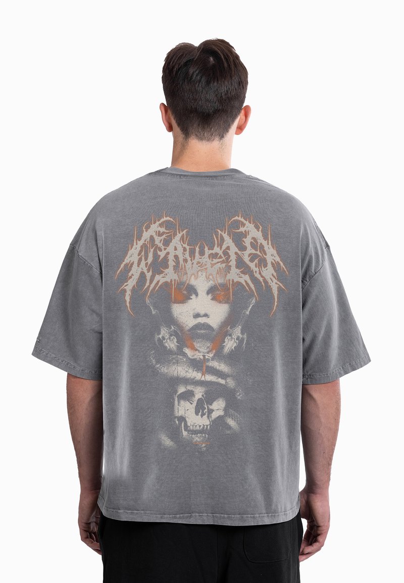 T-shirt cinzenta oversize com um grande gráfico de um rosto e crânio nas costas. O design inclui detalhes em laranja e um acabamento texturizado.