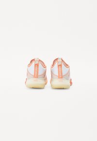 Lightweight athletic shoes with a white and peach color scheme, mesh upper, padded collar, and rubber soles featuring a distinct tread pattern.