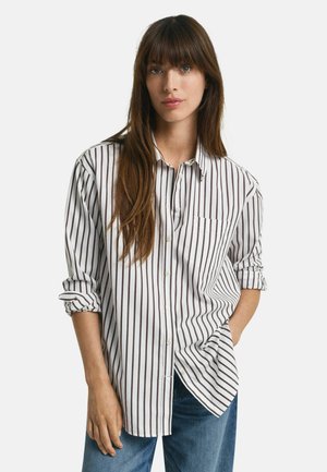 White button-up shirt with vertical burgundy stripes, featuring a chest pocket and rolled-up sleeves, worn with blue denim jeans.