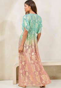 Maxi dress featuring a gradient design from teal to pink, with gold floral patterns, short sleeves, and an elasticated waist.