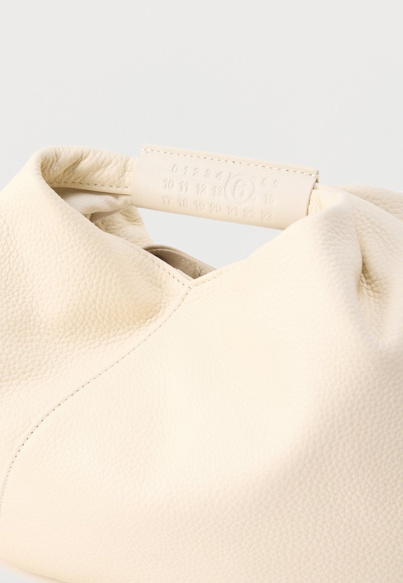 Sac en cuir crème avec une surface texturée, un design froncé et une poignée lisse embossée de chiffres. Esthétique simple et moderne.