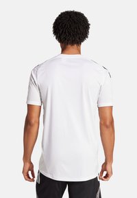 T-shirt de sport blanc à manches courtes, avec un col rond et des accents noirs sur les épaules, fabriqué à partir d'un tissu respirant.